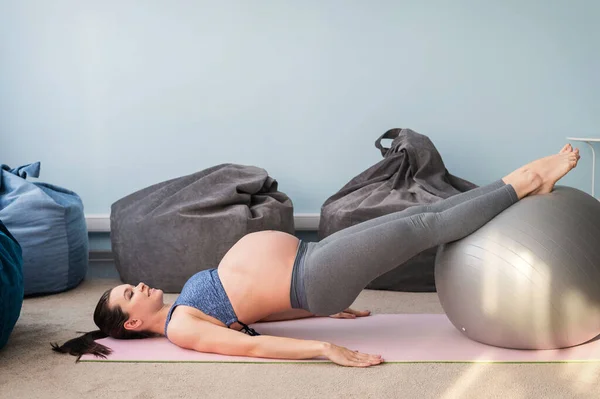 Mulher branca grávida em aptidão com uma bola. Yoga para gestantes. Menina na sala de aula em preparação para o parto. Pilates no último trimestre. — Fotografia de Stock