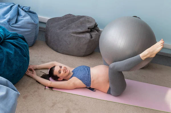 Těhotná evropská žena provádí cvičení s fitness míčem. Očekávaná matka dělá jógu ve 3. trimestru. Dívka ve třídě při přípravě na porod. — Stock fotografie