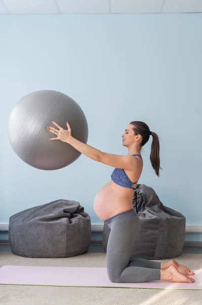 Zwangere blanke vrouw op fitness met een bal. Yoga voor aanstaande moeders. Meisje in de klas ter voorbereiding op de bevalling. Pilates in het laatste trimester. — Stockfoto