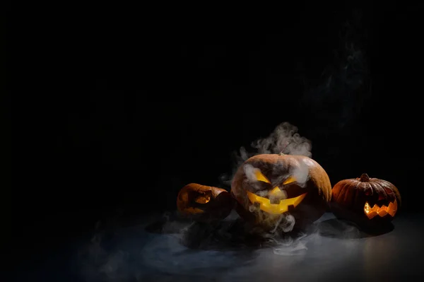 Три тыквы на Хэллоуин в тумане. Традиционное праздничное оформление. Полезно в качестве поздравительной открытки. jack-o-lane курит. — стоковое фото