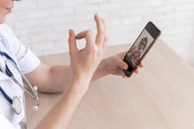 Dost canlısı bir bayan doktor telefonla online danışmanlık yapıyor. Yaşlı bir hasta terapiste danışır. Cep telefonuyla video görüşmesi. Karantina.