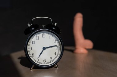 Time for carnal pleasures. Alarm clock and dildo made of cyber leather. Naturalistic vibrator for masturbation.