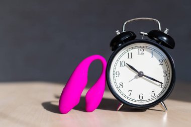 Cinsel haz alma zamanı. Alarm saati ve uyarıcı G noktası. Mastürbasyon için pembe vibratör..