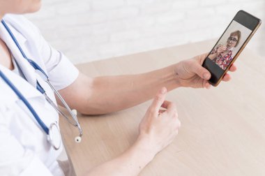 Dost canlısı bir bayan doktor telefonla online danışmanlık yapıyor. Yaşlı bir hasta terapiste danışır. Cep telefonuyla video görüşmesi. Karantina.