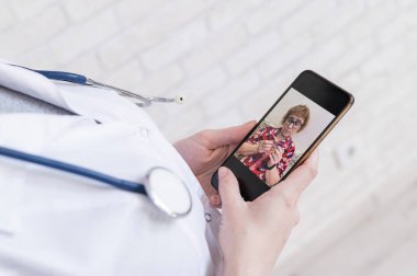 Tanımlanamayan kadın doktor, akıllı bir telefonla online danışmanlık yapıyor. Yaşlı bir kadında koronavirüs var. Cep telefonundan terapiste görüntülü arama. Karantina.