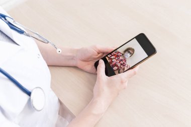 Tanımlanamayan kadın doktor, akıllı bir telefonla online danışmanlık yapıyor. Yaşlı bir kadında koronavirüs var. Cep telefonundan terapiste görüntülü arama. Karantina.