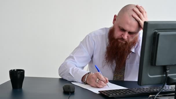 L'homme chauve concentré avec une barbe rouge est engagé dans la paperasserie dans le bureau. Un homme manager en chemise blanche écrit un rapport avec un stylo . — Video