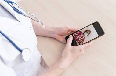 Tanımlanamayan kadın doktor, akıllı bir telefonla online danışmanlık yapıyor. Yaşlı bir kadında koronavirüs var. Cep telefonundan terapiste görüntülü arama. Karantina.