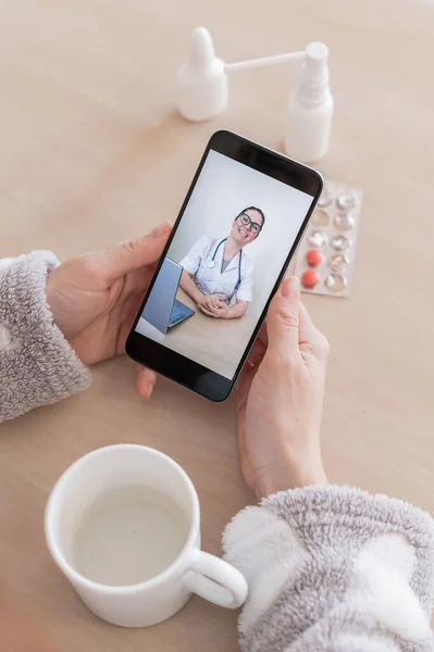 Αγνώριστη γυναίκα σε online διαβούλευση με ένα γιατρό σε ένα κινητό τηλέφωνο. Το κορίτσι είναι άρρωστο και μιλάει με τον θεράποντα γιατρό σε μια βιντεοκλήση από το σπίτι. Κλείσιμο της οθόνης. — Φωτογραφία Αρχείου