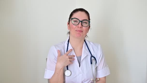 Dost canlısı doktor jestleri yapar ve kameraya konuşur. İnternet üzerinden hastalık önleme tavsiyeleri veren bir sağlık uzmanının portresi. — Stok video