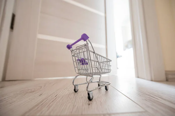 Grocery cart at the open door. Delivery of products. Mini trolley for contactless delivery.