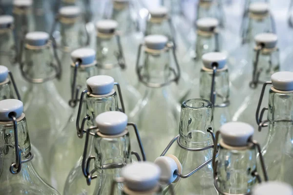 Un primo piano del collo di una bottiglia. Gruppo di bottiglie vuote con tappi di plastica in un negozio sul bancone . — Foto Stock