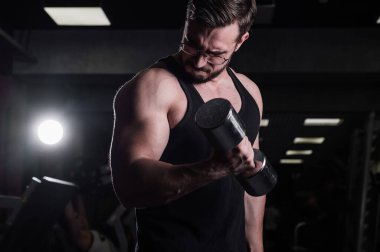 Çabalayan bir adam, pazılar ve trisepsler için halterli egzersiz yapar. Kabartmalı vücut geliştirici. Spor salonunda gözlüklü kaslı adam..