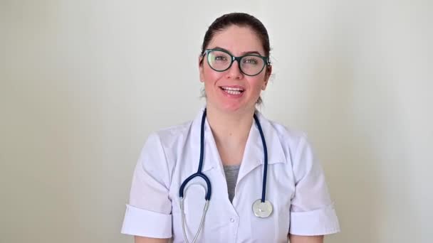 Retrato de un joven médico amigable conversando en la clínica. El médico que atiende da una consulta en línea . — Vídeos de Stock