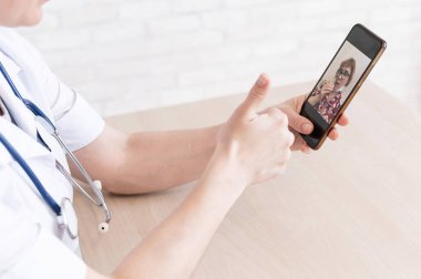 Dost canlısı bir bayan doktor telefonla online danışmanlık yapıyor. Yaşlı bir hasta terapiste danışır. Cep telefonuyla video görüşmesi. Karantina.