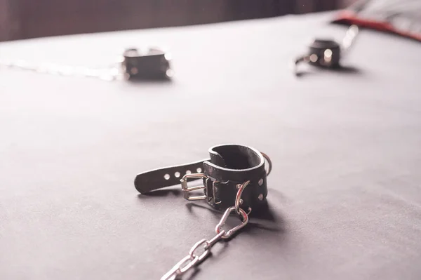 BDSM Leather handcuffs for role-playing games on a gray sheet. Bondage for carnal pleasures. Domination and submission. — Stock Photo, Image