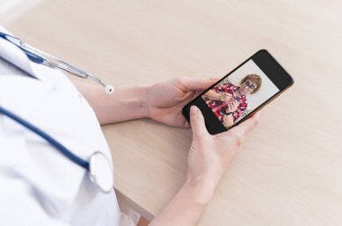 Tanımlanamayan kadın doktor, akıllı bir telefonla online danışmanlık yapıyor. Yaşlı bir kadında koronavirüs var. Cep telefonundan terapiste görüntülü arama. Karantina.