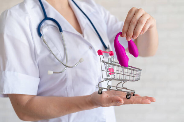 The faceless gynecologist recommends buying a clitoral vaginal vibrator to maintain womens health. The doctor holds a mini trolley and a masturbator for vivid orgasms.