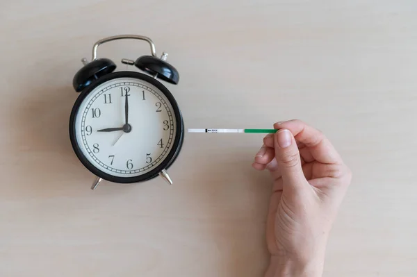 La mujer tiene prueba de ovulación negativa y despertador. Concepto de reloj biológico de fertilidad femenina. No es el momento adecuado para concebir un bebé . — Foto de Stock