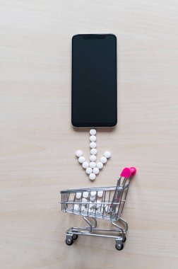Çevrimiçi eczane kavramı. İnternetten ilaç satın almak. Eczacıların teslimatı. Kapsüllü mini tramvay ve siyah ekranlı akıllı telefon..
