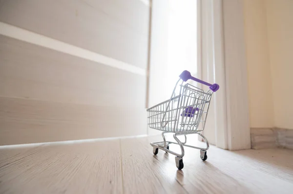 Um carrinho de compras à porta aberta. Entrega de produtos. Mini carrinho para entrega sem contato . — Fotografia de Stock