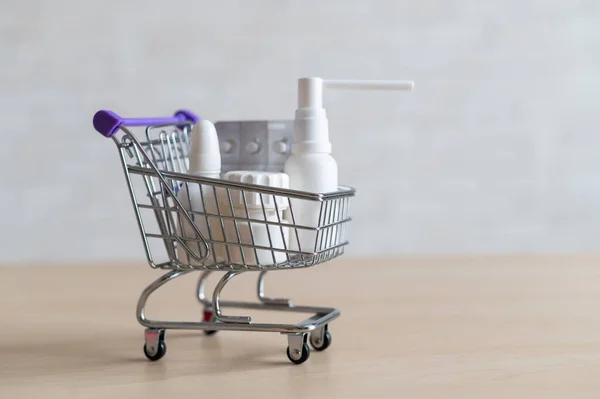 Carrinho de compras com comprimidos e drogas. Frascos de medicamentos diferentes em um carrinho mini . — Fotografia de Stock