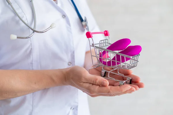 The faceless gynecologist recommends buying a clitoral vaginal vibrator to maintain womens health. The doctor holds a mini trolley and a masturbator for vivid orgasms.