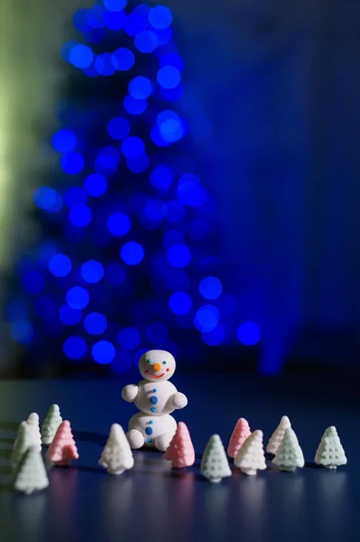 Bonhomme de neige mignon et petits arbres de Noël faits de guimauves sur le fond des lumières de Noël. Guirlande d'ampoules sur un arbre. Bonne année. — Photo