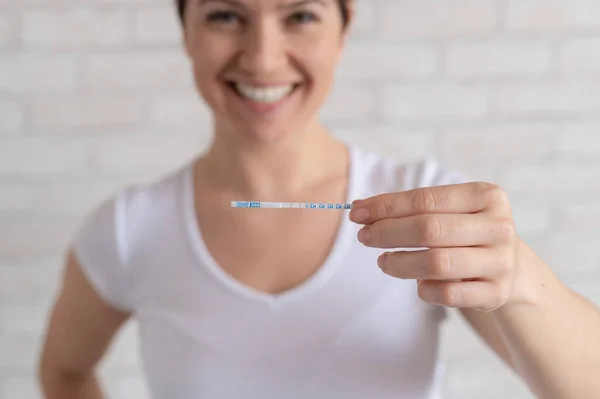 La mujer feliz muestra una prueba de ovulación positiva. El concepto de fertilidad femenina y alta hormona luteinizante. El momento adecuado para concebir un hijo . — Foto de Stock