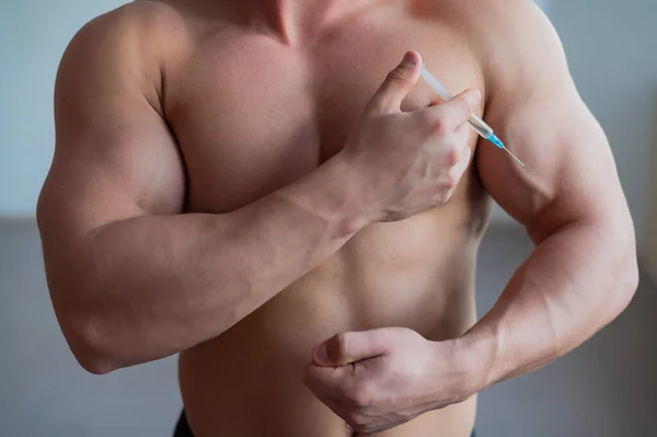 Un homme musclé avec un torse nu tient une seringue de drogue. bodybuilder méconnaissable se met stéroïdes. Athlète triche pour gagner de la masse musculaire . — Photo