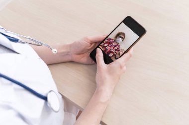 Tanımlanamayan kadın doktor, akıllı bir telefonla online danışmanlık yapıyor. Yaşlı bir kadında koronavirüs var. Cep telefonundan terapiste görüntülü arama. Karantina.