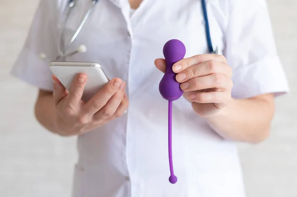 Unrecognized gynecologist recommends a kegel simulator to maintain womens health. The doctor synchronizes the vibrator with the smartphone. Device for the muscles of the pelvic floor. — Stock Photo, Image