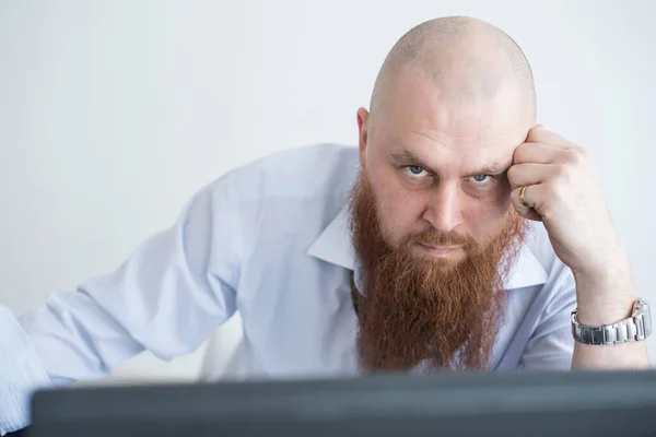 A focused bald man with a red beard stares intently at the camera. Male manager in a white shirt is angry at work. — Stock Photo, Image