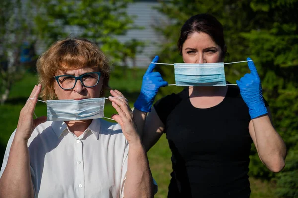 Мама і дочка надягали медичні маски проти поширення інфекції. Дві жінки похилого віку і середнього віку захищені від коронавірусу.. — стокове фото