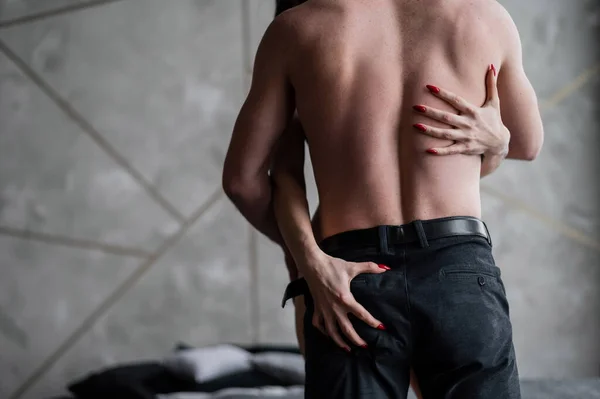Mãos femininas nas costas de um homem irreconhecível. Um jovem casal abraça-se no quarto. Amor e paixão em um relacionamento . — Fotografia de Stock