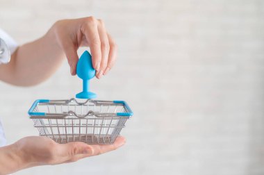 Yüzsüz jinekolog minyatür alışveriş sepetlerine anal tıpa takıyor. Doktor alternatif seks için cihazı tutuyor. Pratisyen, güvenlik için silikon bir oyuncak öneriyor..