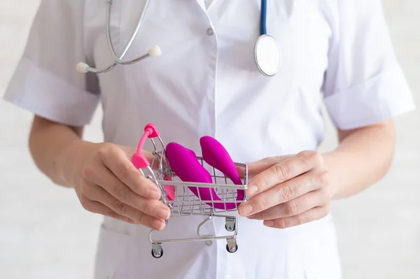 O ginecologista sem rosto recomenda comprar um vibrador vaginal do clitóris para manter a saúde das mulheres. O médico segura um mini carrinho e um masturbador para orgasmos vívidos . — Fotografia de Stock