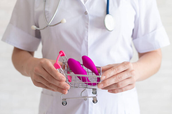 The faceless gynecologist recommends buying a clitoral vaginal vibrator to maintain womens health. The doctor holds a mini trolley and a masturbator for vivid orgasms.