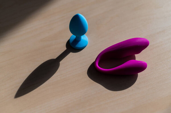 A set of sex toys from latex. Blue silicone butt plug and pink vaginal clitoral vibrator. Curved Massager Point G Stimulator