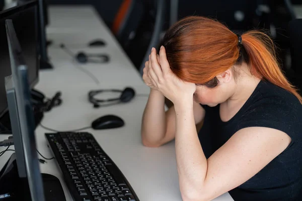 Trött kvinna arbetsnarkoman t-shirt i ett tomt kontor. Kvinnlig IT-chef i avslappnade kläder vid datorn. En tjej med huvudvärk jobbar övertid. Migrän och depression på grund av problem i arbetet — Stockfoto