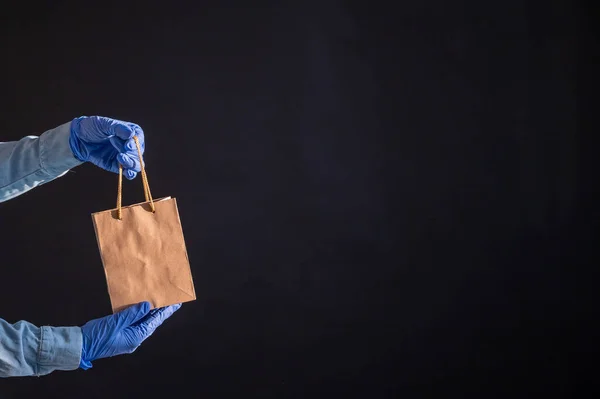 Express-Lieferung nach Hause in der Epidemie des Coronavirus. Kurier in Handschuhen mit Papiertüte. Verpackungen aus umweltfreundlichem Recyclingmaterial. Online-Kauf von Produkten in Quarantäne. — Stockfoto