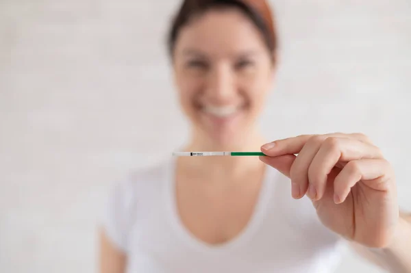 La mujer feliz muestra una prueba de embarazo negativa. El concepto de fertilidad femenina. Gonadotropina coriónica humana. Un niño de tira libre . — Foto de Stock