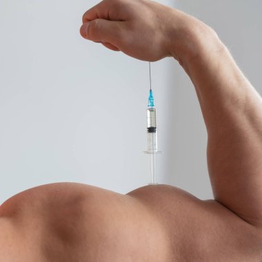 Şırıngalı bir erkeğin yakın çekimi. Kesik pazılı bir adam. Tanınmayan vücut geliştirici kendini büyüme hormonu testosteronu haline getiriyor..