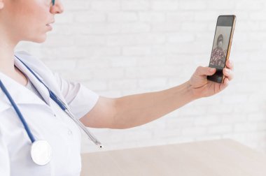 Tanımlanamayan kadın doktor, akıllı bir telefonla online danışmanlık yapıyor. Yaşlı bir kadında koronavirüs var. Cep telefonundan terapiste görüntülü arama. Karantina.