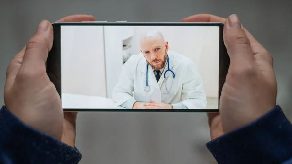 Medicina online. O paciente conversa com o médico através de um link de vídeo enquanto está em casa. Um homem dá uma consulta médica remota em um smartphone. Uma mulher está doente em casa e chama o terapeuta . — Fotografia de Stock