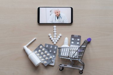Bir erkek eczacı ilaç satın almayı öneriyor. Akıllı telefon oklarının en üst görüntüsü tabletlerden, mini alışveriş arabalarından ve masada duran ilaçlardan seriliydi. Çiftlik temsilcisi.
