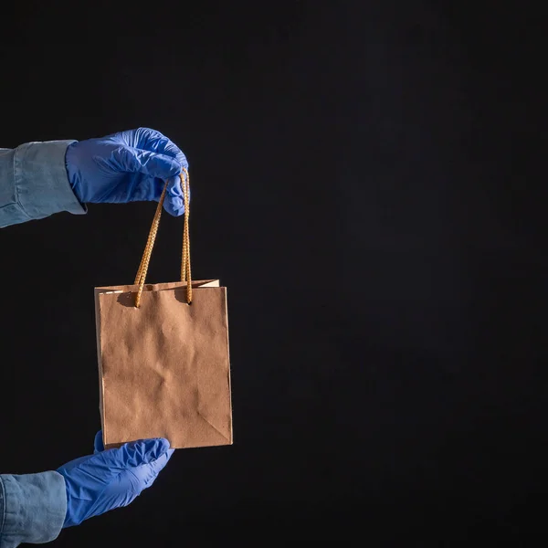 Express delivery to the epidemic of coronavirus. Closeup of couriers hands in rubber gloves with a paper bag with handles. Packaging made from eco friendly recycled material. Donation to quarantine. — Stock Photo, Image