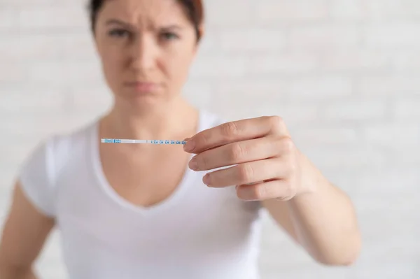 Sad woman shows a negative ovulation test. The concept of female infertility and low luteinizing hormone. Frustrated girl.