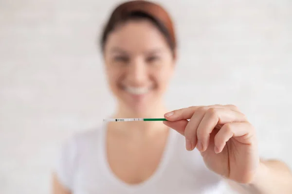 Щаслива жінка показує позитивний тест на вагітність. Поняття жіночої родючості. Людський хоріонічний гонадотропін. Дві смужки очікують дитину . — стокове фото