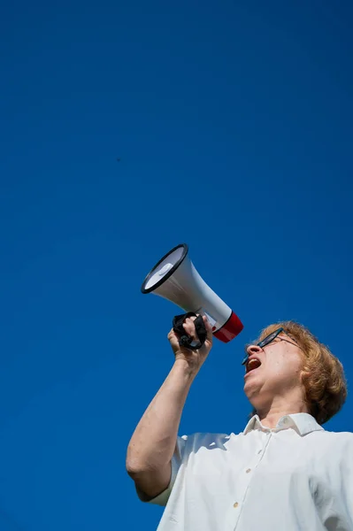 感情的な高齢女性はメガホンに要求をプッシュします.怒った引退した女性が高齢者の権利のために戦っている。集会の女性指導者は声高に主張する. — ストック写真